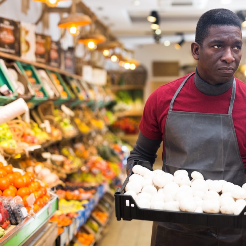 Focused,African,Man,Working,At,Farmer,Market,,Arranging,Fresh,Mushrooms